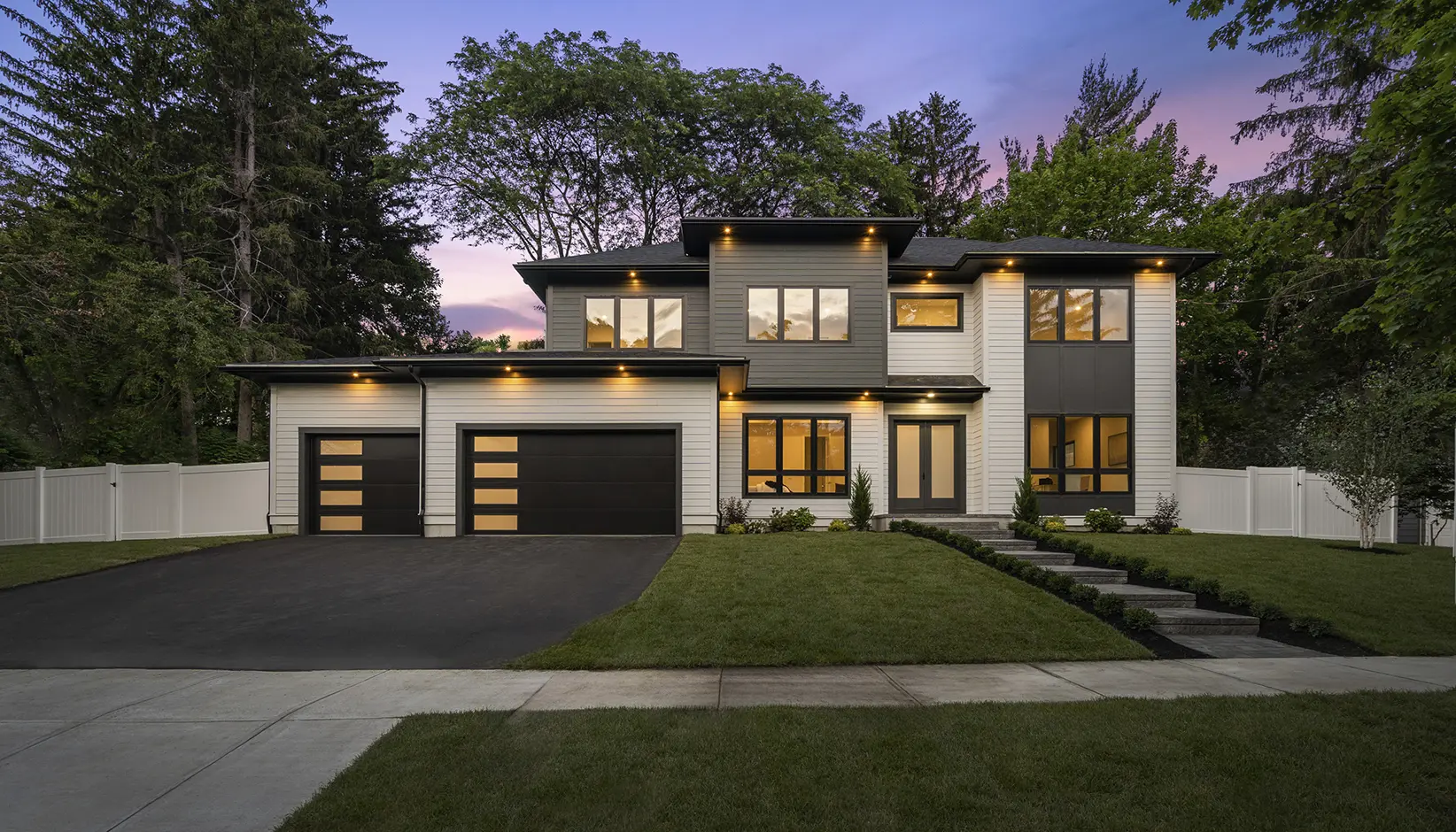 Two black flush-panel garage doors with vertical columns of frosted glass on a modern home